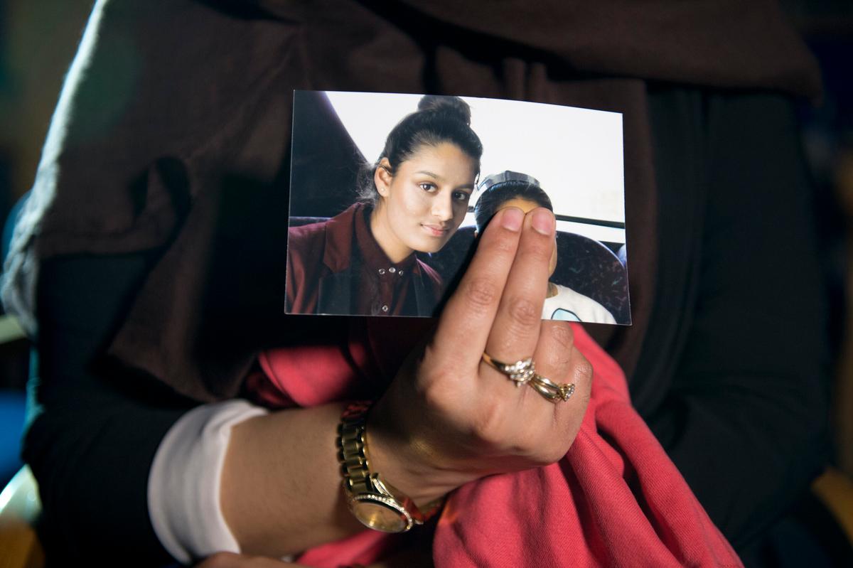 The older sister of Shamima Begum, Renu Begum, holds a photo of her sister with a child. Two of her fingers obscure the child