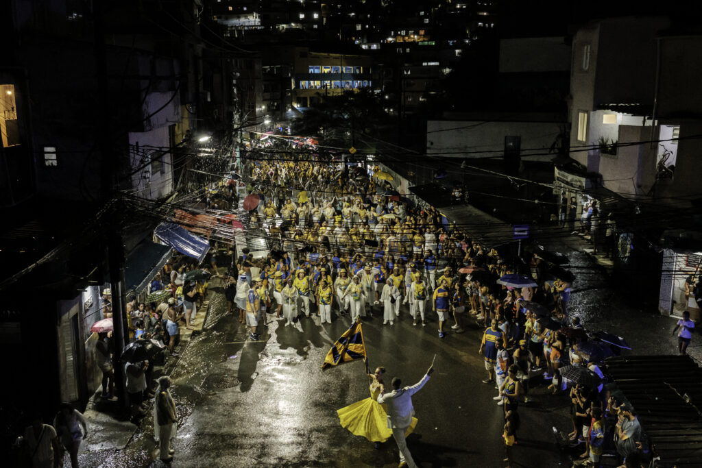 During the Unidos da Tijuca samba school’s final street rehearsal, the Mestre-Sala and Porta-Bandeira wing leads a large group of members through the streets near Favela do Borel, in the Tijuca neighborhood of Rio de Janeiro, Brazil.