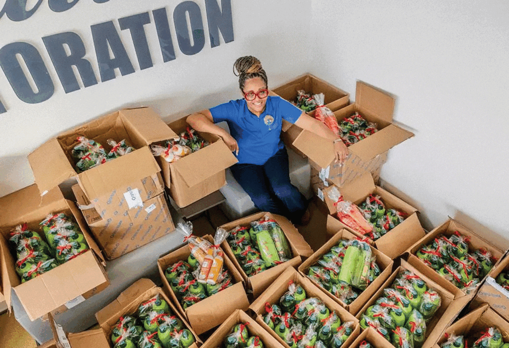 A photo of a woman surrounded by cardboard boxes with packs of shampoo and conditioner. 