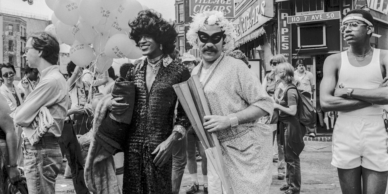 American gay liberation activist Marsha P Johnson (1945 - 1992) (center left, in dark outfit and black hair), along with unidentified others, on the corner of Christopher Street and 7th Avenue during the Pride March (later the LGBT Pride March), New York, New York, June 27, 1982. (Barbara Alper/Getty Images)