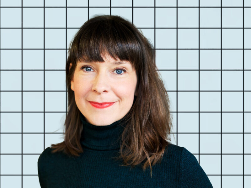 A photo of Györgyi Gálik on a blue grid background.